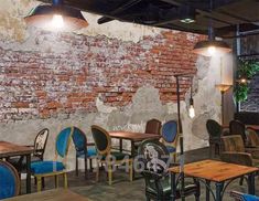 the interior of a restaurant with blue chairs and wooden tables, brick wall behind it