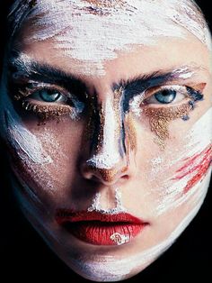 a woman's face is painted with white paint and red lipstick on her cheek