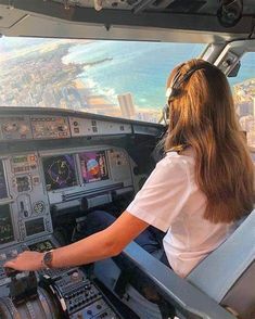 a woman sitting in the cockpit of an airplane looking out at the city and ocean