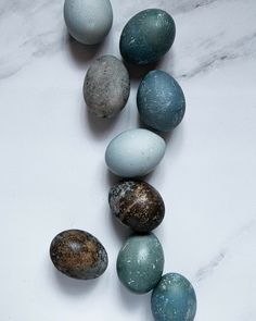 several different colored eggs on a white marble surface