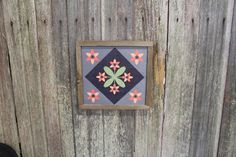 a wooden fence with a small quilt hanging on it