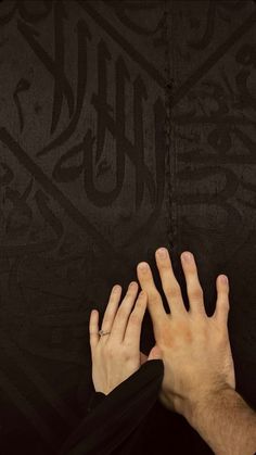 two hands reaching up towards each other in front of a black background with arabic writing