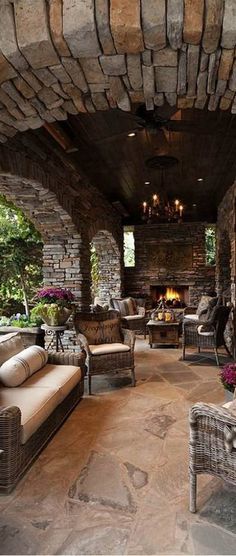 an outdoor living room with stone walls and furniture