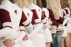 a group of women standing next to each other wearing white and maroon uniforms with their hands on their hips