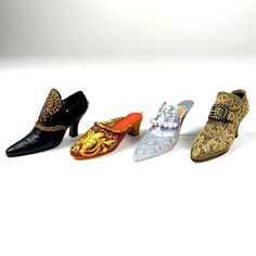 four different types of shoes are lined up on a white surface and one is decorated with gold, silver, and black