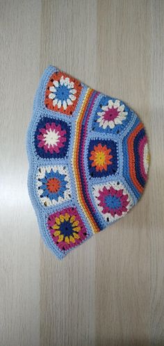 a crocheted pot holder is sitting on a table next to a wooden surface