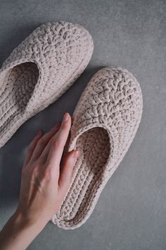 a woman's hand is touching the bottom of a pair of crocheted slippers