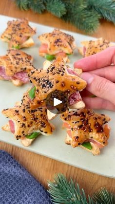 someone is picking up some food from a platter on a table with pine branches