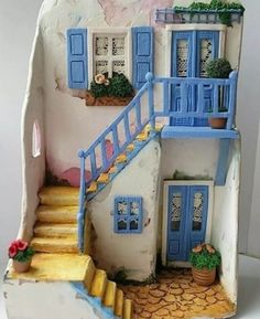 a doll house with blue shutters and steps leading up to the front door is shown