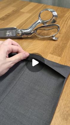 someone cutting fabric with scissors on a table