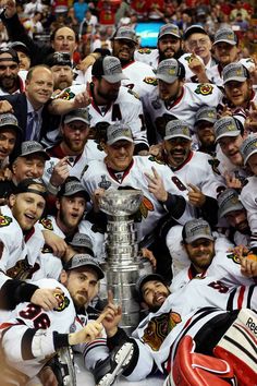 hockey players pose with the stanley cup