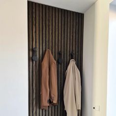 two coats are hanging on the wall next to each other in front of a coat rack