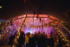 a group of people standing under a tent covered in lights