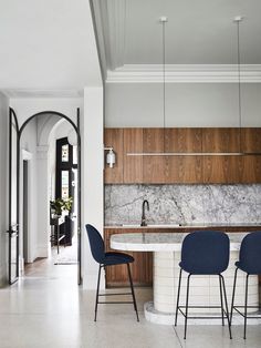 a kitchen with marble counter tops and blue chairs