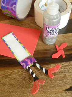 some crafting supplies are laying out on a wooden table with scissors, tape and glue