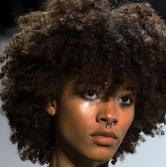 a close up of a person with an afro on the catwalk at a fashion show