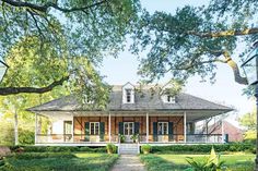 a large brick house sitting in the middle of a lush green field next to trees