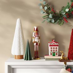 christmas decorations are displayed on a mantel in front of a wreath and nutcracker