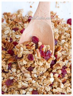 a wooden spoon filled with granola and cranberries