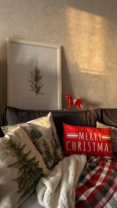 pillows and blankets are arranged on the bed in front of a christmas tree framed print