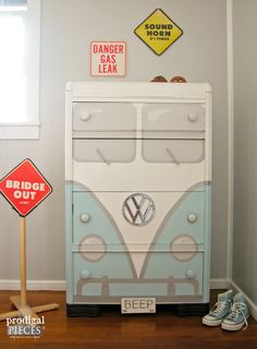 a blue and white toy van sitting on top of a wooden floor next to a sign