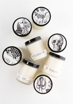 six jars of body butter sitting next to each other on a white surface with black and white designs