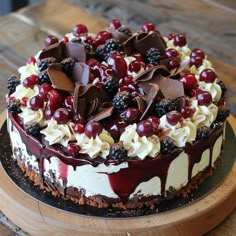 a cake with chocolate, cream and berries on top sitting on a wooden platter