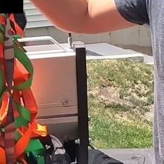 a man standing next to a pile of luggage on top of a lawn covered in green and orange ribbons