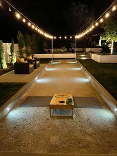 an outdoor area with lights and benches on the side walk at night, lit up by string lights