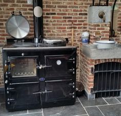 an old fashioned stove sitting in front of a brick wall next to a small sink