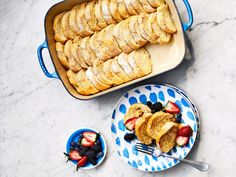 an assortment of pastries and desserts on plates next to a bowl of fruit