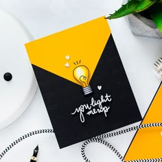 a yellow and black greeting card with a light bulb on it, surrounded by other items