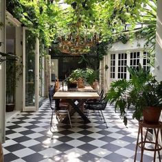 an outdoor dining area with black and white checkered tile flooring, potted plants on the table