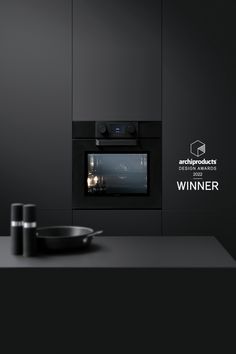 a black kitchen with an oven and pan on the counter