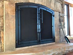 a fireplace with an iron screen on the front and back sides, next to a window