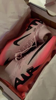 a pair of pink and black nike shoes in a box