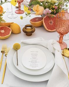 a table setting with grapefruits and flowers