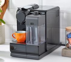 a coffee maker sitting on top of a counter next to a cup and saucer