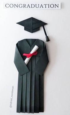 an origami graduation cap and gown made out of black paper with a red ribbon