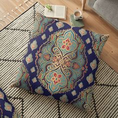 a blue floor pillow sitting on top of a rug next to a book and cup