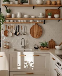 a kitchen with white cabinets and wooden shelves filled with pots, pans and utensils