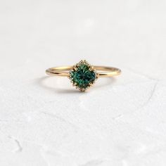 a gold ring with a green stone in the center on a white surface, close up