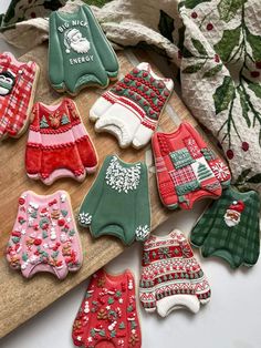 decorated cookies on a cutting board with christmas sweaters and snowflakes around them