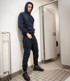 a man standing in front of an open door wearing a hoodie and sweatpants