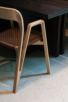 a wooden chair sitting next to a table on top of a tile floor with white walls