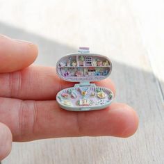 someone is holding a small toy in their hand with pictures inside it and the lid opened