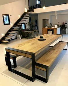 a wooden table sitting in the middle of a living room next to a stair case