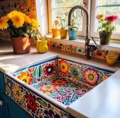 a kitchen sink with colorful flowers painted on the front and side, next to a window