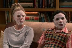 two people with facial masks sitting on a couch