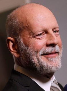 an older man with grey hair and beard smiling